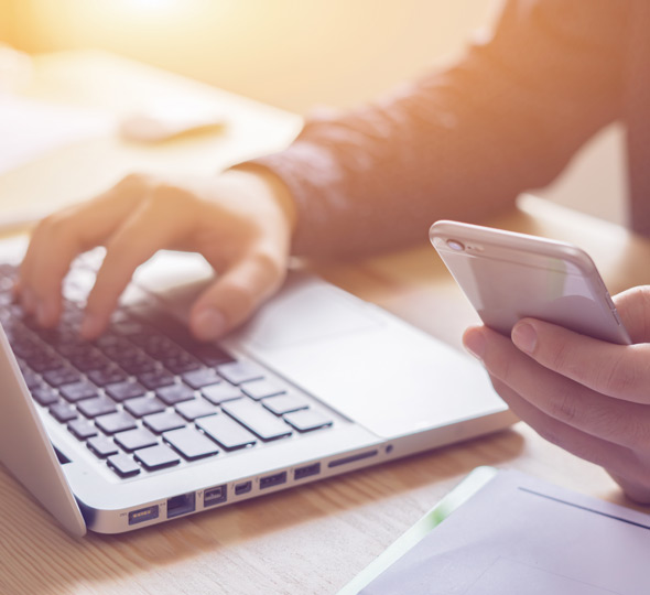 A man accessing files on his phone and his laptop by using a Cloud Content Management Software for the Healthcare Industry